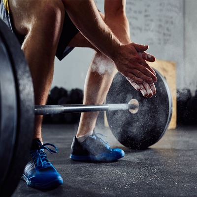 Atleta si prepara a sollevare un bilanciere per uno stacco da terra in palestra